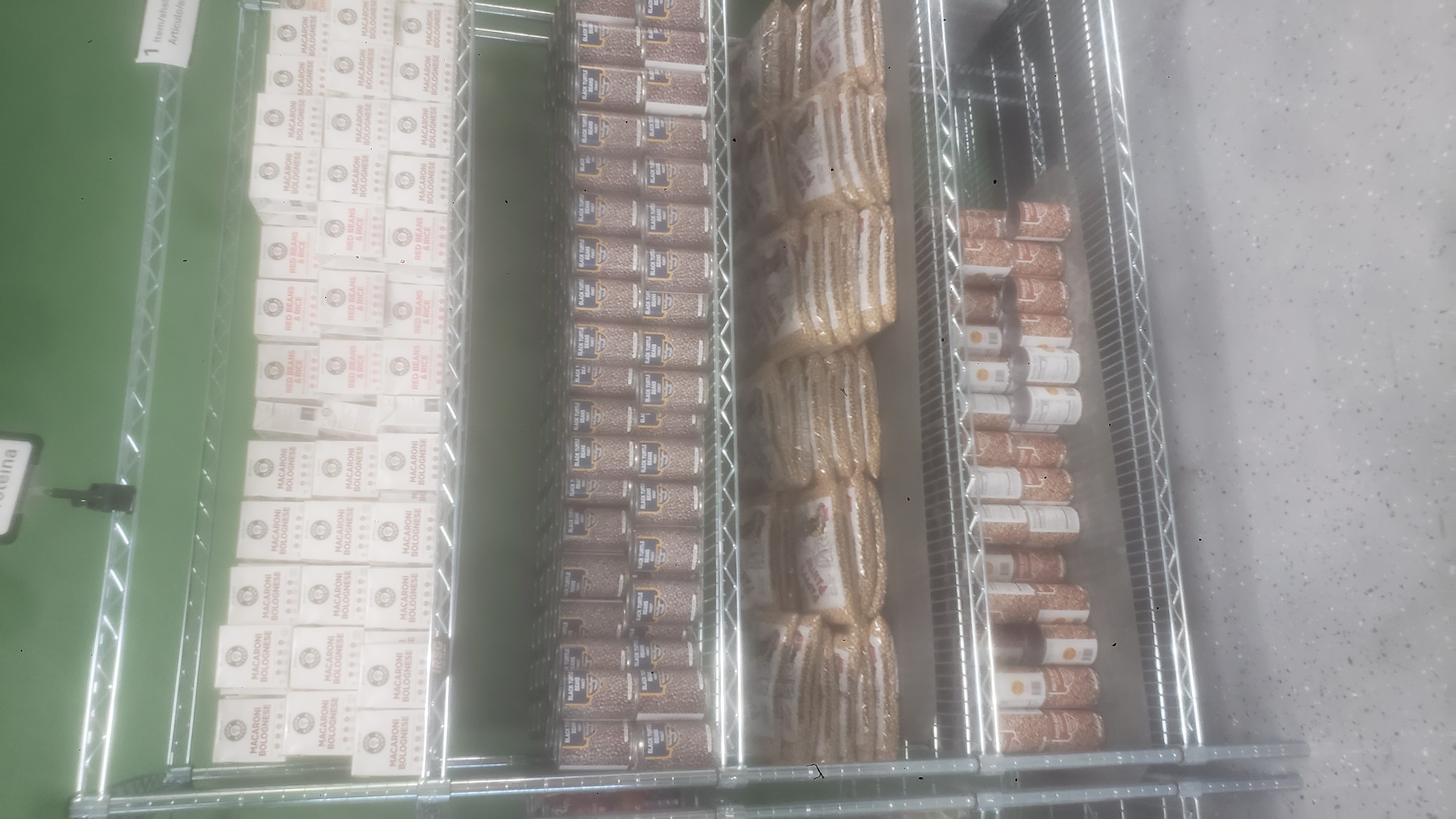 Canned pinto beans, bags of chickpeas, canned black turtle beans, and ready-to-eat meals on a four tier shelf.